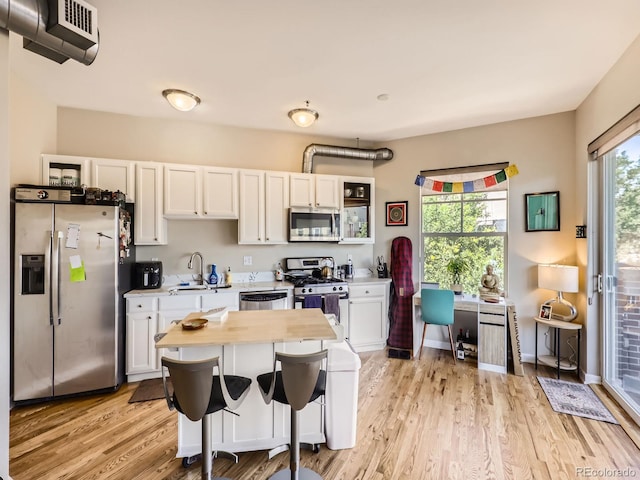 1441 Central Unit 305, Denver, CO 80211 - kitchen with stainless steel appliances, light wood-style floors, white cabinets, a desk, and wooden counters
