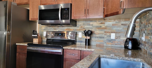 1034 Van Fossan Ln, Fort Garland, CO 81133 - kitchen featuring stainless steel appliances, decorative backsplash, light stone counters, a sink, and brown cabinets