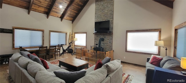 1034 Van Fossan Ln, Fort Garland, CO 81133 - living area with a wood stove, light wood-style flooring, high vaulted ceiling, wooden ceiling with exposed beams, and baseboards