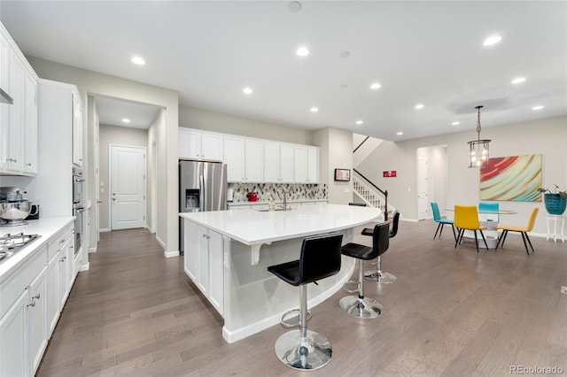 kitchen with tasteful backsplash, white cabinetry, and an island with sink