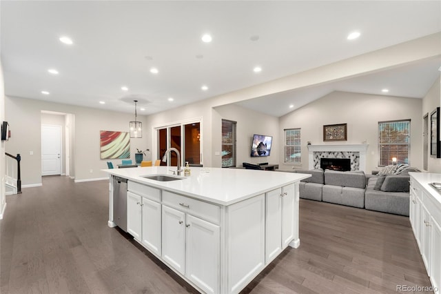 kitchen with dishwasher, sink, white cabinets, a premium fireplace, and a center island with sink