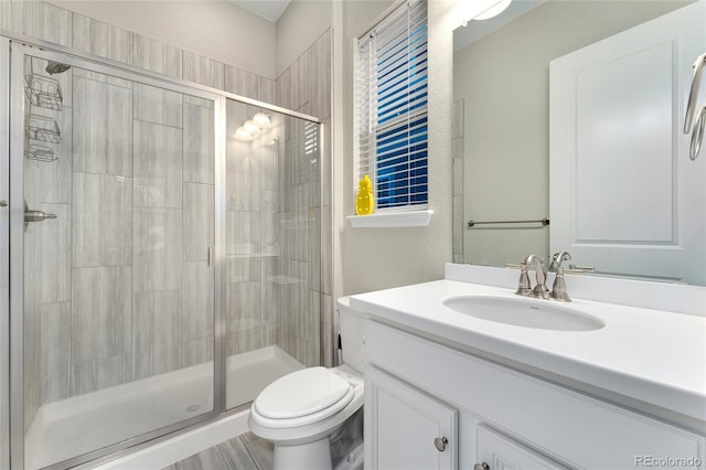 bathroom with vanity, a shower with door, and toilet