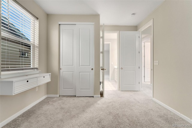 unfurnished bedroom featuring light carpet and a closet