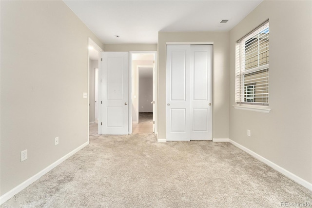 unfurnished bedroom with light carpet and a closet