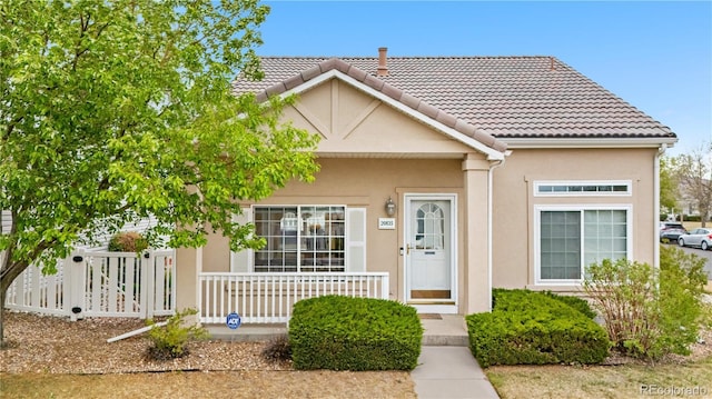 20835 E 47th Ave, Denver, CO 80249 - view of front of house with covered porch, stucco siding, a tile roof, and fence