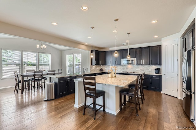 12578 Hudson Ct, Thornton, CO 80241 - kitchen featuring stainless steel appliances, a kitchen island, a sink, a kitchen breakfast bar, and backsplash
