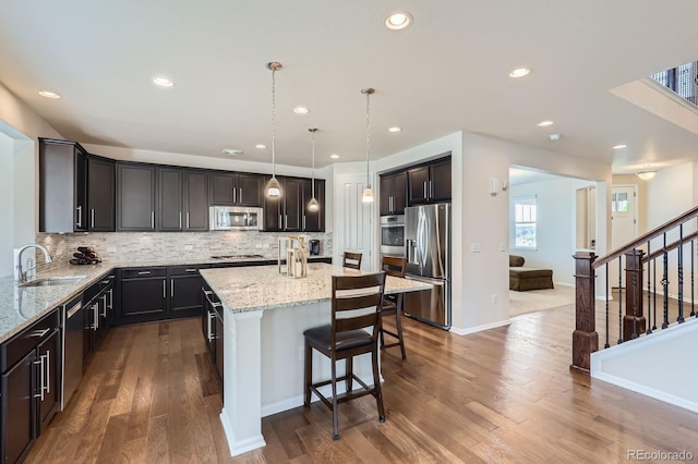 12578 Hudson Ct, Thornton, CO 80241 - kitchen with appliances with stainless steel finishes, a sink, light stone countertops, a kitchen island, and a breakfast bar