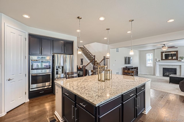 12578 Hudson Ct, Thornton, CO 80241 - kitchen featuring stainless steel appliances, a ceiling fan, light stone countertops, a kitchen island, and dark wood-type flooring