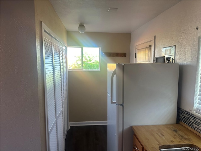 6671 E 73rd Pl, Commerce City, CO 80022 - kitchen with freestanding refrigerator, a textured wall, wood counters, and wood finished floors