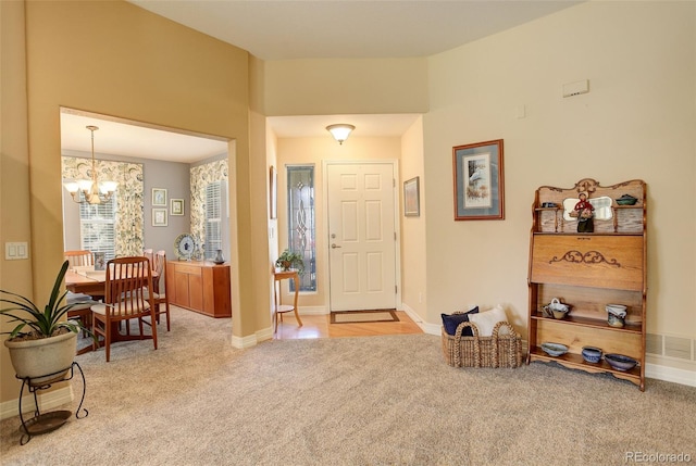 foyer entrance with visible vents, carpet flooring, baseboards, and an inviting chandelier