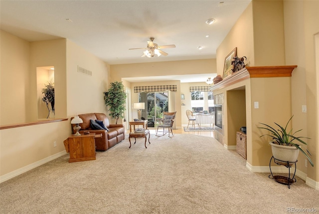 carpeted living room with a fireplace, visible vents, baseboards, and ceiling fan