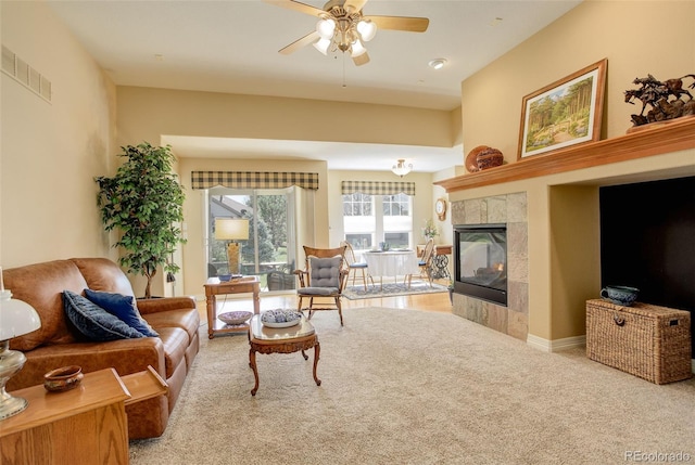 living room with visible vents, ceiling fan, carpet, and a tile fireplace