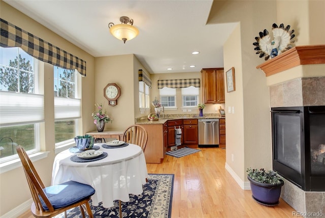 dining area featuring light wood-style floors, a healthy amount of sunlight, and a tile fireplace