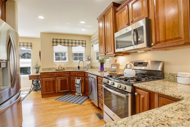 kitchen featuring light stone countertops, light wood-type flooring, visible vents, a sink, and stainless steel appliances