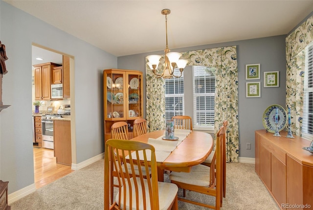 dining room with light colored carpet, a notable chandelier, and baseboards