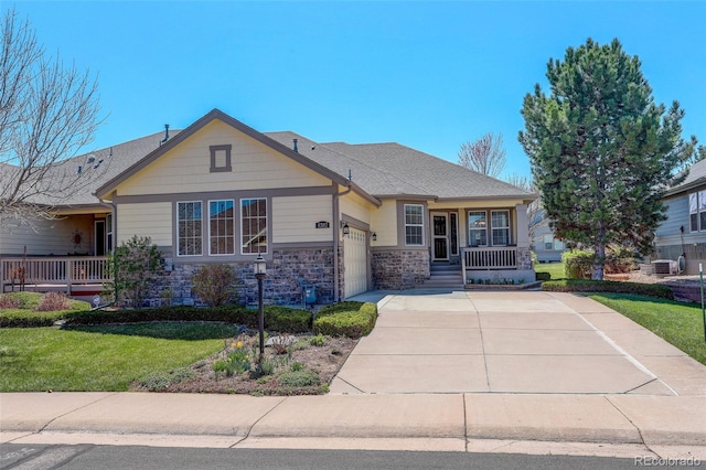 view of front of property featuring cooling unit, covered porch, stone siding, a garage, and driveway