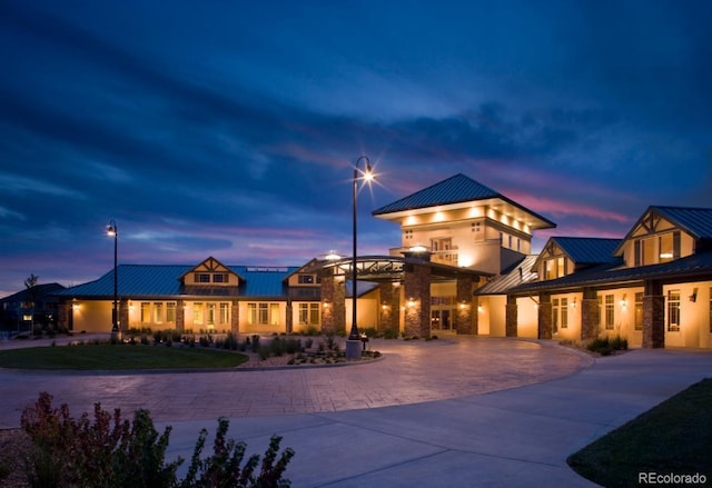 view of front of home featuring stone siding, a standing seam roof, metal roof, and curved driveway