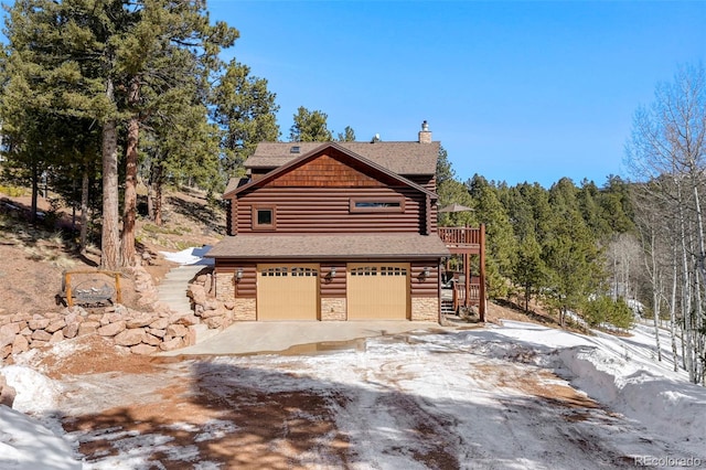 log cabin featuring a garage, log exterior, concrete driveway, stone siding, and stairway