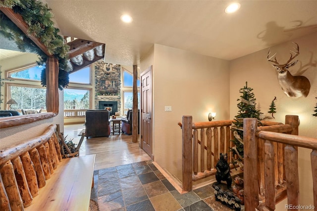 hallway featuring an upstairs landing, recessed lighting, baseboards, and stone tile floors