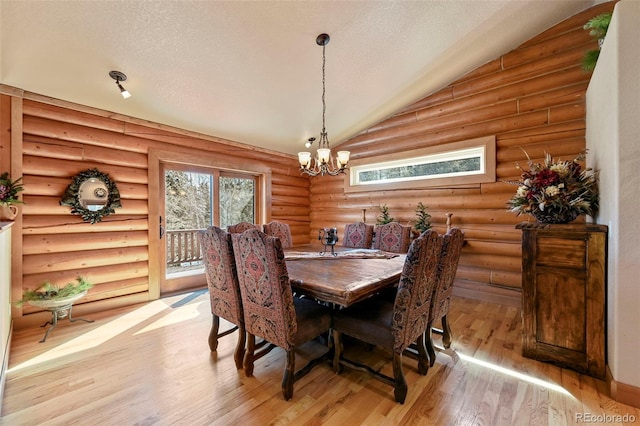 dining area featuring vaulted ceiling, a textured ceiling, a chandelier, and light wood-style floors