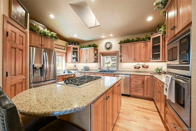 kitchen with appliances with stainless steel finishes, a kitchen island, a kitchen bar, and glass insert cabinets