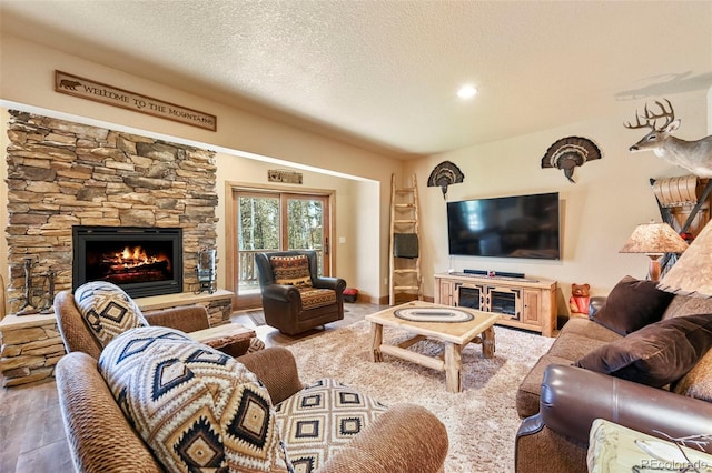 living room with a fireplace, a textured ceiling, and wood finished floors