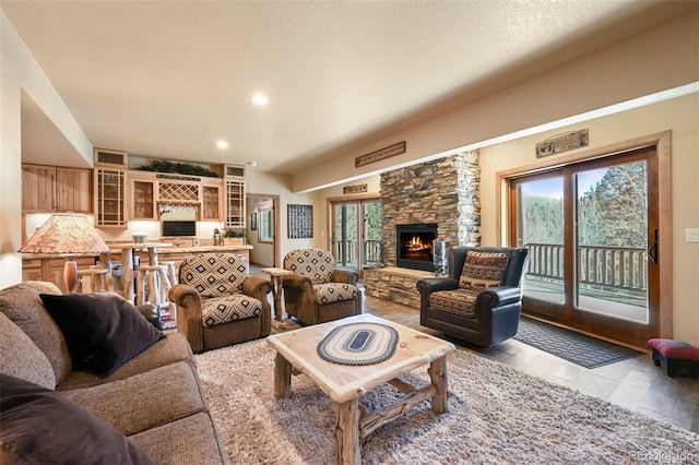 living room featuring light wood-type flooring, recessed lighting, a stone fireplace, and a textured ceiling