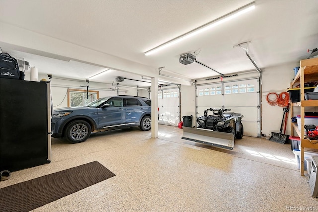 garage featuring freestanding refrigerator and a garage door opener