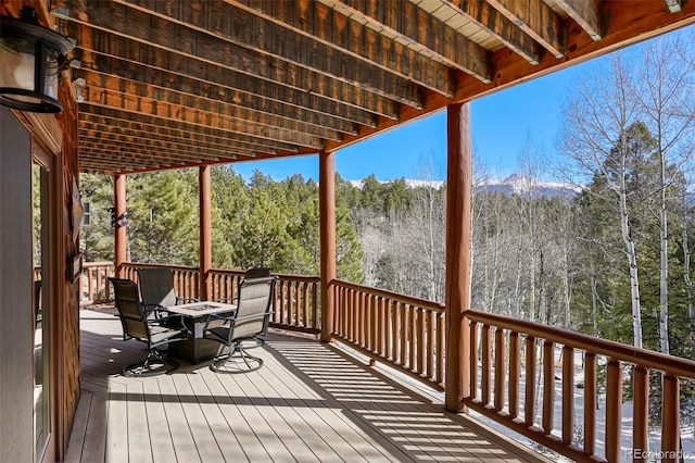 wooden deck with outdoor dining space and a wooded view