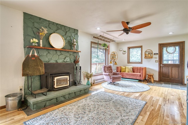 living room featuring ceiling fan, baseboard heating, and light wood-type flooring