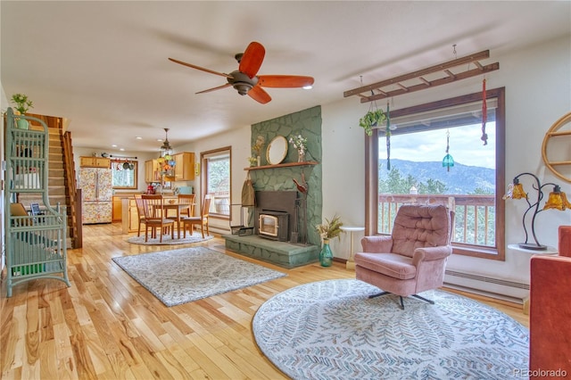 living room with ceiling fan, a baseboard radiator, a mountain view, and light hardwood / wood-style floors