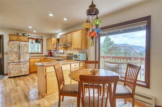 kitchen with light hardwood / wood-style flooring, refrigerator, a mountain view, decorative light fixtures, and a baseboard radiator