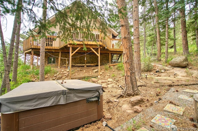 rear view of house featuring a wooden deck and a hot tub