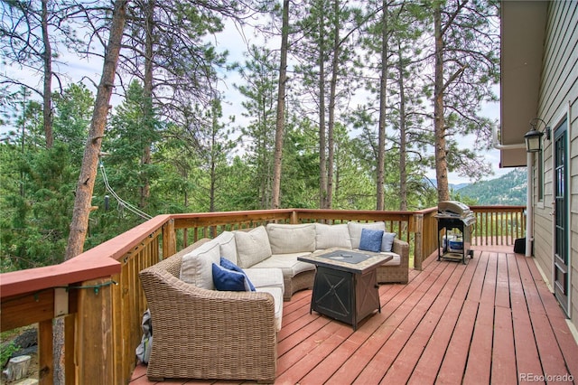 wooden terrace featuring a grill and an outdoor living space with a fire pit