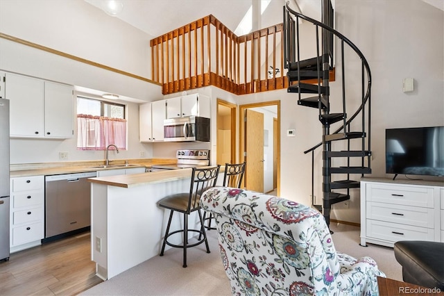 5250 S Huron Way Unit 5-308, Littleton, CO 80120 - kitchen with appliances with stainless steel finishes, white cabinetry, light countertops, a kitchen breakfast bar, and a high ceiling