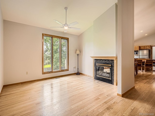 9670 W 69th Ave, Arvada, CO 80004 - unfurnished living room featuring lofted ceiling, light wood-style floors, a high end fireplace, a ceiling fan, and baseboards