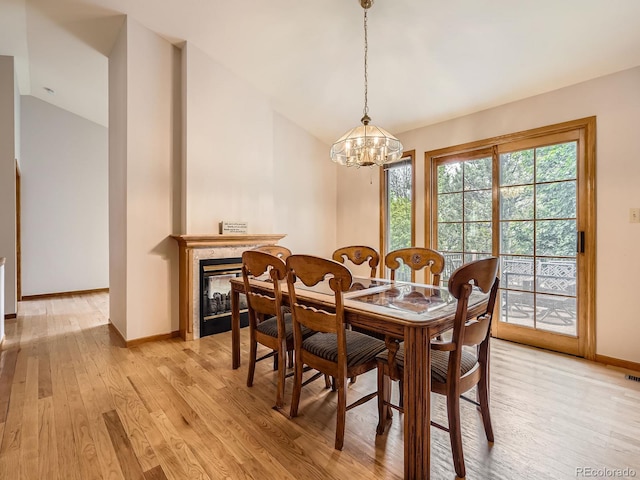 9670 W 69th Ave, Arvada, CO 80004 - dining area featuring vaulted ceiling, light wood-style floors, baseboards, a chandelier, and a glass covered fireplace