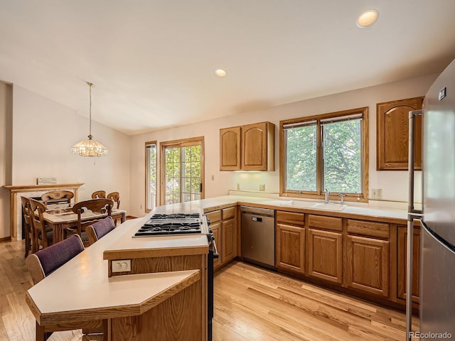 9670 W 69th Ave, Arvada, CO 80004 - kitchen featuring appliances with stainless steel finishes, a sink, light wood finished floors, light countertops, and a breakfast bar