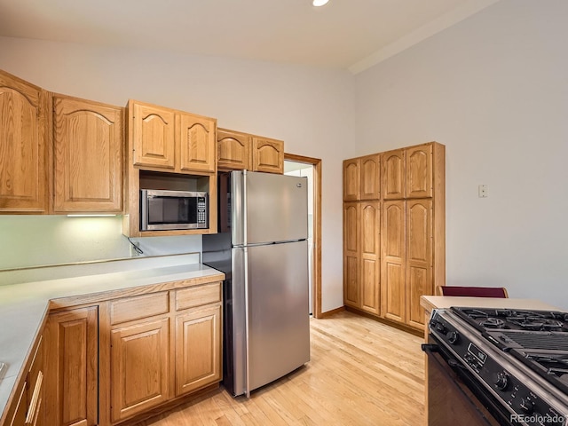 9670 W 69th Ave, Arvada, CO 80004 - kitchen with appliances with stainless steel finishes, light wood-style flooring, light countertops, and vaulted ceiling