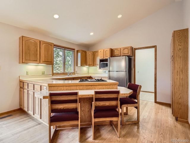 9670 W 69th Ave, Arvada, CO 80004 - kitchen featuring stainless steel appliances, open shelves, light wood finished floors, lofted ceiling, and light countertops