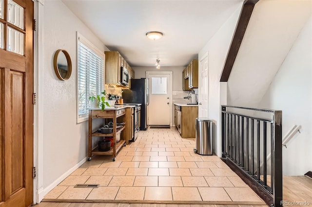 kitchen featuring light tile patterned floors, sink, appliances with stainless steel finishes, decorative backsplash, and beamed ceiling