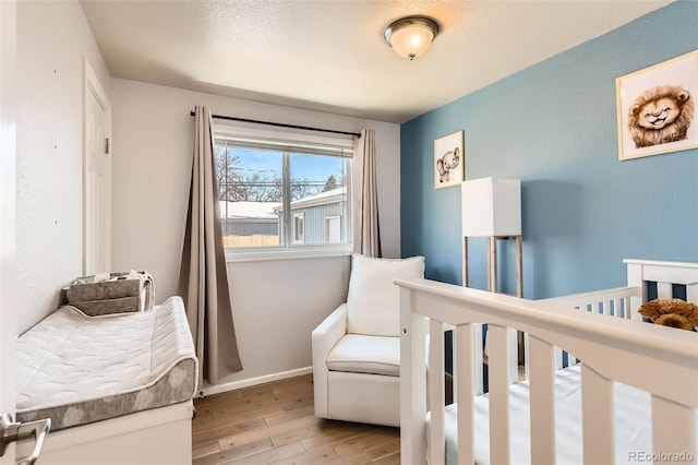 bedroom featuring a crib and light hardwood / wood-style flooring