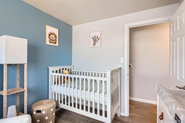 bedroom featuring a crib and dark hardwood / wood-style flooring