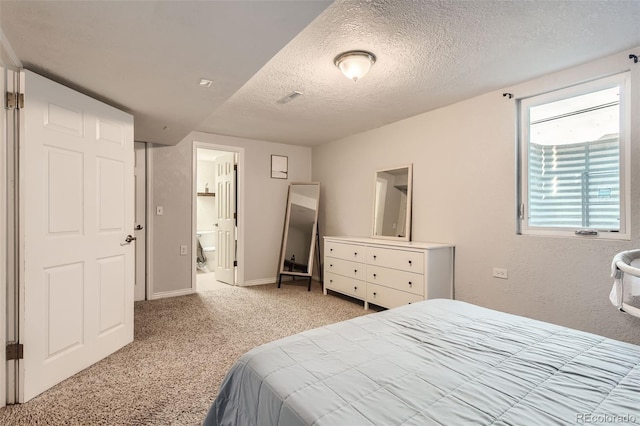 carpeted bedroom with connected bathroom and a textured ceiling