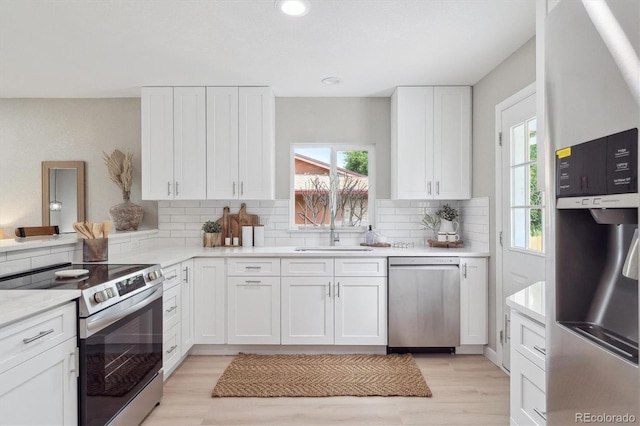 13051 W Jewell Cir, Lakewood, CO 80228 - kitchen featuring stainless steel appliances, white cabinetry, decorative backsplash, light wood finished floors, and recessed lighting