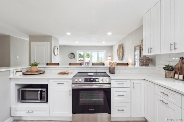 13051 W Jewell Cir, Lakewood, CO 80228 - kitchen with stainless steel appliances, light countertops, white cabinets, recessed lighting, and decorative backsplash