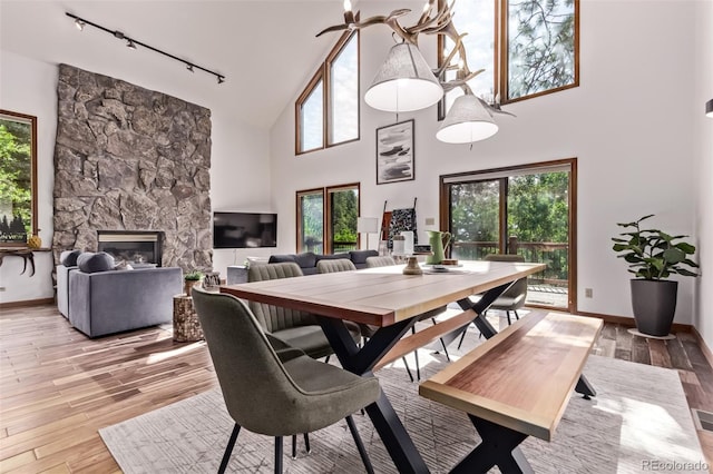 20223 Goins Dr, Morrison, CO 80465 - dining space featuring track lighting, high vaulted ceiling, light wood-type flooring, and a stone fireplace