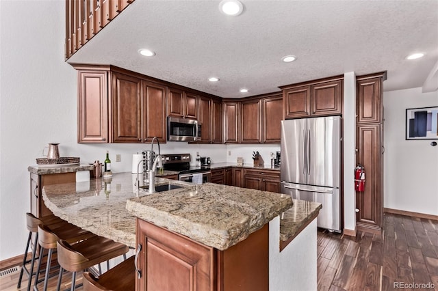 20223 Goins Dr, Morrison, CO 80465 - kitchen featuring appliances with stainless steel finishes, a peninsula, light stone countertops, dark wood-type flooring, and recessed lighting