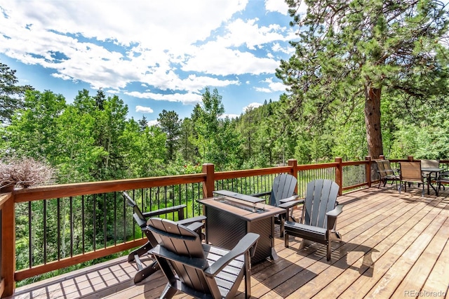 20223 Goins Dr, Morrison, CO 80465 - wooden terrace with outdoor dining area and a wooded view