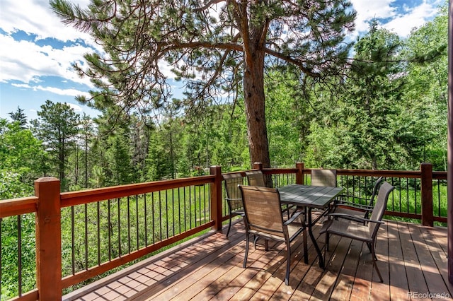 20223 Goins Dr, Morrison, CO 80465 - wooden terrace with outdoor dining area and a wooded view